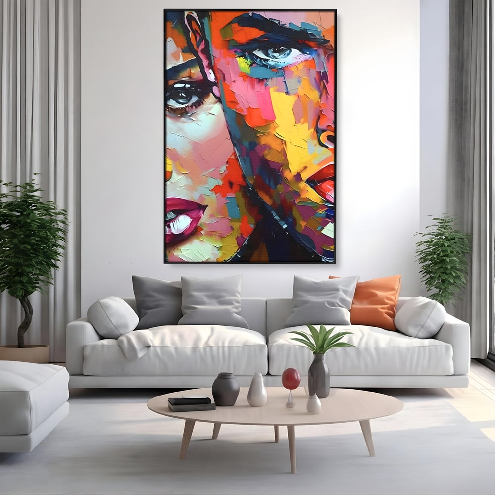 Tablou canvas cu tablou canvas cu chipuri in culori vibrante, in rama de aluminiu negru, pe perete intr-un living